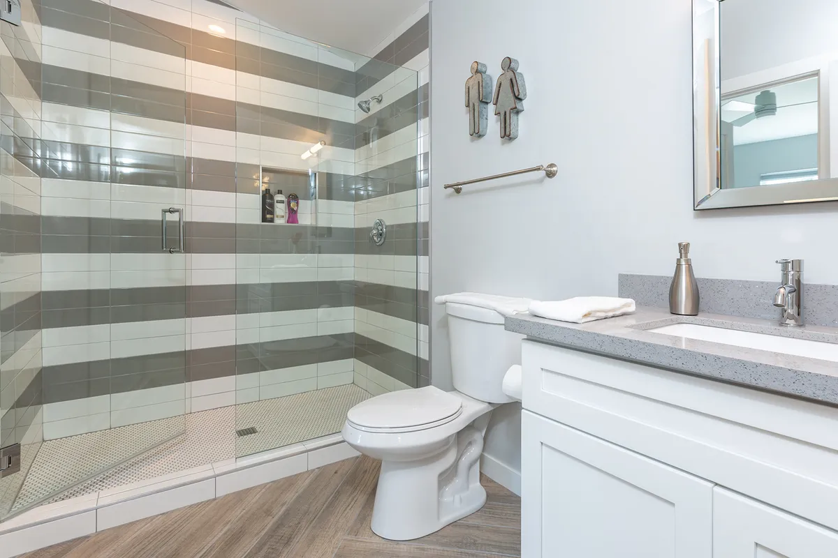 A modern bathroom with a glass shower stall, double sink vanity, and sleek fixtures. The space is bright and fresh, offering a functional and serene environment for personal care.