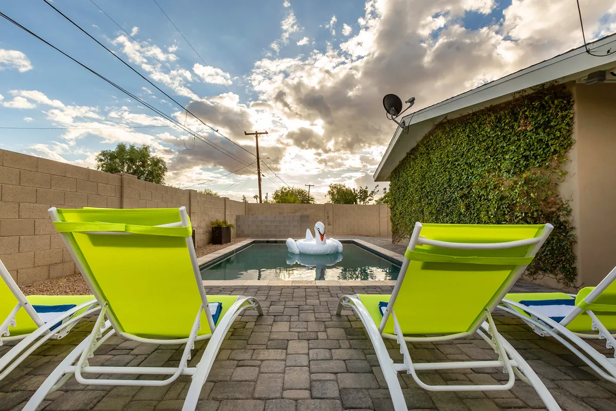 A cheerful and inviting scene shows a gleaming swimming pool with an inflatable swan, surrounded by multiple lounge chairs. The space is ideal for both lively pool parties and serene morning swims.